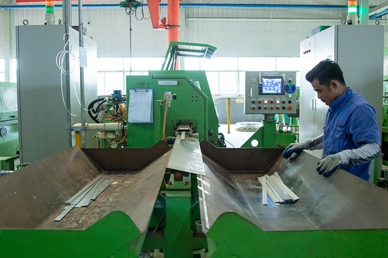 Factory worker produces metal strips to build automobile parts.