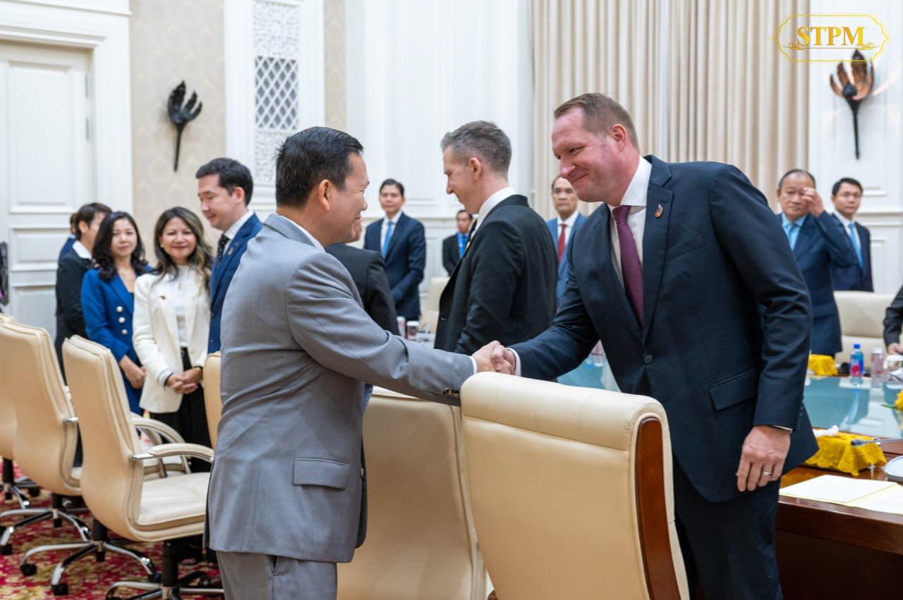 Prime Minister Hun Manet and Devin Barta, President of AmCham Cambodia, shaking hands.